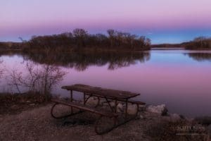 A picnic table and the afterglow of sunset at a lake.