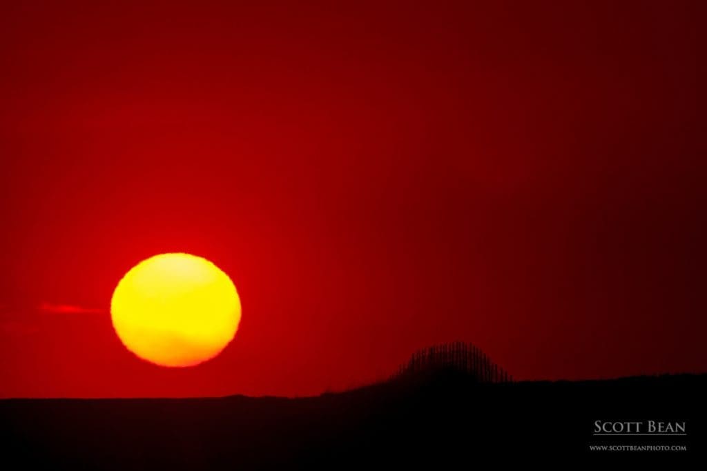 The setting sun and a silhouetted section of fence